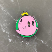 Pink ghost pin with yellowish crown in a green circle. Glows in the dark.